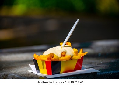 Belgian street and fast food, paper box in colors of Belgian flag with fried potato frit chips and mayonnaise sauсe.