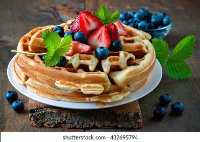 Belgian waffles with strawberries, blueberries and syrup, homemade healthy breakfast, toned image, selective focus