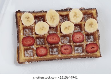 Belgium waffle with banana and strawberries slices on white plate  - Powered by Shutterstock