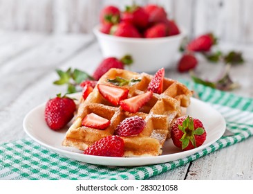 Belgium waffles with strawberries and mint on white plate