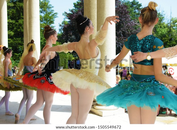 Belgrade, Serbia - 06.08.2019:\
Four young  ballerinas are bowing to the crowd after an outdoor\
performance. They are in colorful costumes and the weather is hot\
and sunny. 