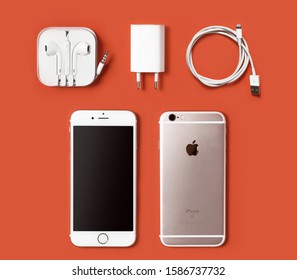 Belgrade, Serbia - December 12 2019 : Apple iPhone 6s full pack items. Iphone with baterry charger and headphones isolated on orange background.
