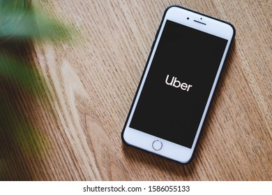 Belgrade, Serbia - December, 2019: Uber Logo On The Iphone Smartphone Screen, Laying On Wooden Background. Flatlay Picture. Uber Is Smartphone App Offering Transportation Solutions.