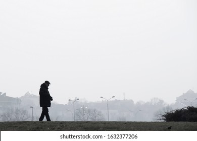 Belgrade, Serbia - January 26, 2020: Silhouette Of Elderly Man Walking Alone On Ada, On A Foggy Polluted Winters Day