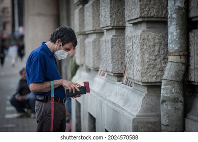 BELGRADE, SERBIA - MAY 24, 2021: Male Client Reading A Book In Front Of A Bookstore Wearing A Respiratory Face Mask In Belgrade, During The Coronavirus Covid 19 Health Crisis.

