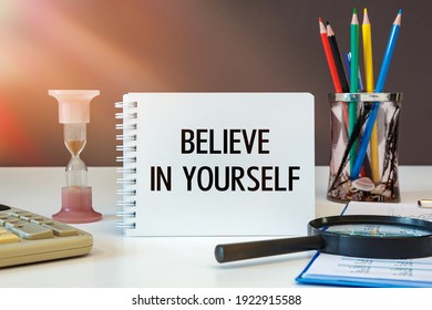Believe in yourself is written on a notepad on an office desk with office accessories.