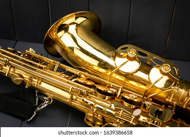 Bell And Body Of A Golden And Shiny Saxophone With Strap On Gray Wooden Background