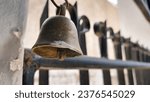 A bell hanging in front of the gate is rusty due to age