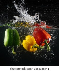 Bell peppers soak underwater with black background                  