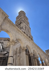 The bell tower of Diocletian's Palace in Split, Croatia, rises majestically with its Romanesque architecture, carved stone details and arched windows adorn the structure.