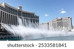 The Bellagio Hotel and Casino with its iconic fountain show in Las Vegas, Nevada, under a clear blue sky.