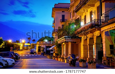 Bellagio, lake Como, Milan, Italy. Nighttime street with blue sky and lights of outdoor lanterns. Picturesque italian architecture of famous luxury Alpine health resort.
