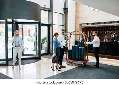 Bellboy helping guests with their luggage cart in hotel hallway. He takes guests' luggage to their rooms. - Powered by Shutterstock