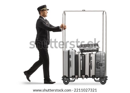 Bellboy pushing suitcases on a hotel luggage cart isolated on white background [[stock_photo]] © 