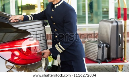 Bellboy taking baggage of guest from thee car to his room Сток-фото © 