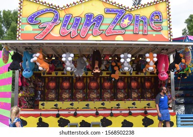 Belleville, Ontario, Canada - July 13 2019: A Fairground Worker Stands Next To A Fun Zone Carnival Game At A Summer Fair