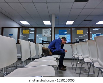 Bellevue, WA / USA - November 1st, 2019: Bellevue DMV waiting room with white chairs and a man sitting waiting.