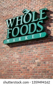 Bellevue, Washington / USA - April 1 2019:  Whole Foods Market sign on a red brick wall, an Amazon company offering Prime discount on organic produce and groceries, with space for text on the bottom