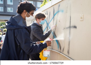 Bellevue, Washington / USA - June 1 2020:  Community members wearing masks cleaning graffiti after Black Lives Matter Protests