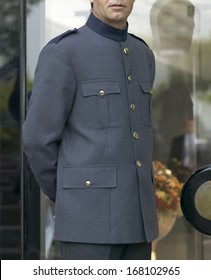 Bellhop With Grey Uniform Opening Door Of A Hotel Building