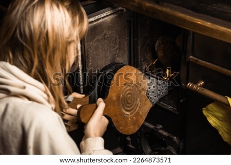 bellows for kindling the fireplace. A woman is lighting a stove.