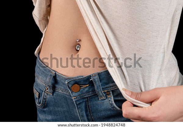 Belly button or navel piercing of sexy young woman\
isolated on black background. Close up macro shot. Horizontal macro\
photography view.