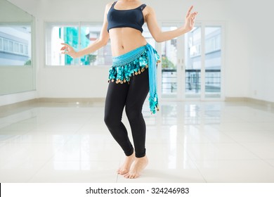 Belly dancer in legging and hip scarf dancing in the class