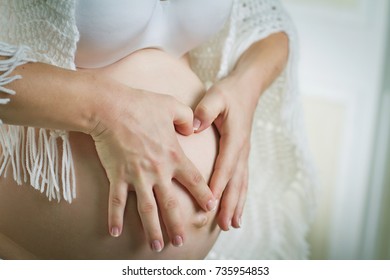 Belly of the pregnant woman and the heart of her hands - Shutterstock ID 735954853
