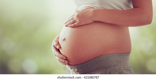 belly of a pregnant woman on a light natural background