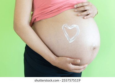 belly young pregnant woman unrecognizable applying moisturizing cream of stretch marks on the belly, heart-shaped. skin care concept during pregnancy and maternity. - Powered by Shutterstock