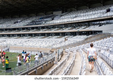 BELO HORIZONTE, MINAS GERAIS / BRAZIL - FEB 7, 2016: Visitors Walking Around The Grandstand Grey Seats Rows And The Pitch Of Mineirao Stadium. At The Back Some Luxury Boxes And Upper Grandstand Seats.