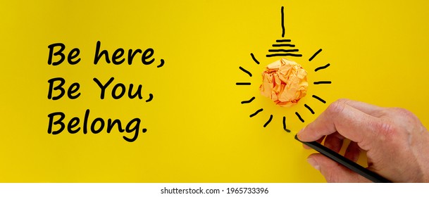 Belonging symbol. Businessman writing words 'be here, be you, belong', isolated on yellow background. Light bulb icon. Business, belonging and better inclusion, belong here concept. Copy space. - Shutterstock ID 1965733396