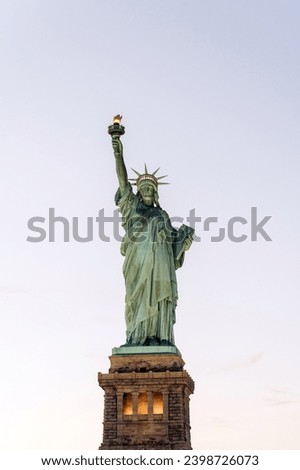 From below of aged stone famous Statue of Liberty located on pedestal in New York city against cloudless dull sky