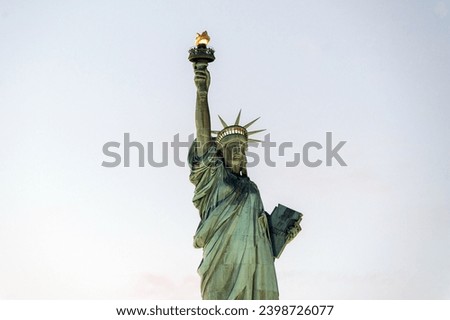 From below of aged stone famous Statue of Liberty located on pedestal in New York city against cloudless dull sky