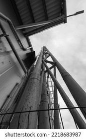 From Below Black And White Pipes Installed Near Wall Outside Factory Building On Cloudy Day