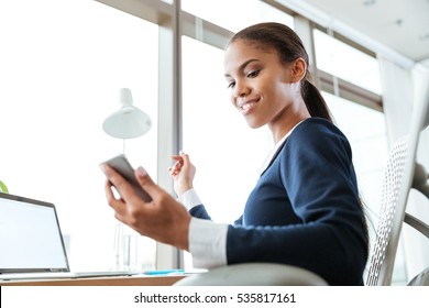 From Below Image Of Smiling Afro Business Woman In Dress Looking At Phone In Office