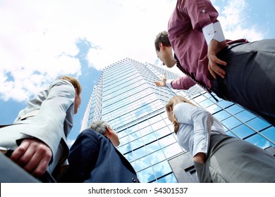 Below view of business partners pointing at modern office building against cloudy sky