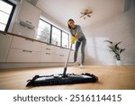 Below view of happy woman cleaning parquet floor with a mop.