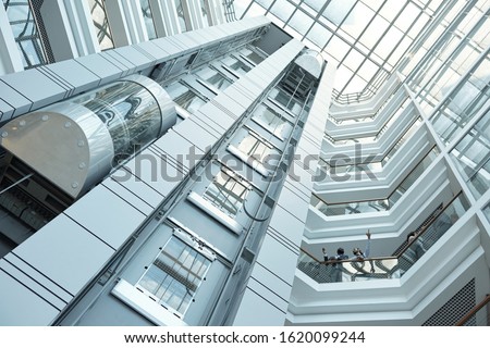 Below view of moving elevator, walls and balconies of contemporary business center that can be used as background