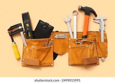 Belt with different construction tools and wallet on beige background