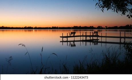 Bemidji, Minnesota, the Best Town in Minnesota is seen across Lake Irving, the first lake on the Mississippi River, after sunset in summertime. A dock is seen in the foreground in this night photo.