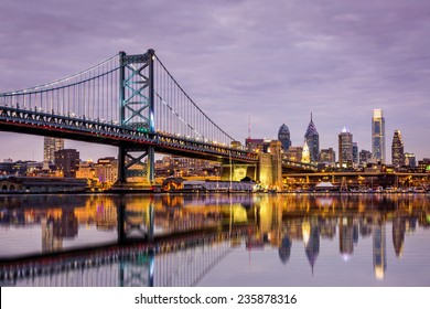 Ben Franklin bridge and Philadelphia skyline reflected in the Delaware river under a purple twilight