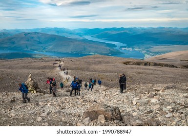 Ben Nevis, UK - August 24 2019: People Hike On Ben Nevis. Fort William (and Some Other Scottish Villages), Loch Linnhe And Loch Eil Are In The Background.