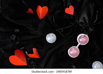 Ben Wa vaginal pleasure balls, Kegel balls on black background, top view, red paper hearts on background