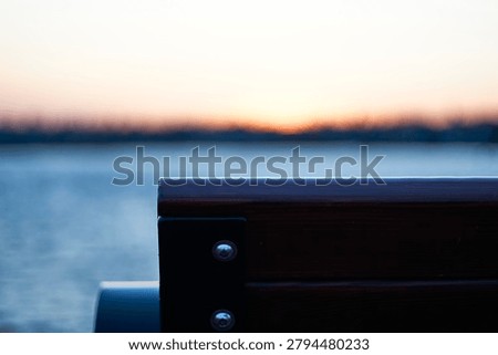 A bench by the ocean at sunset. 