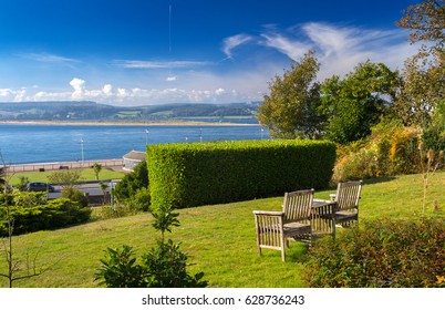 Bench or chairs with a table on the lawn with a magnificent view of the fusion of the Exe River with the English Channel (La Manche). City of Exmouth. Devon. UK