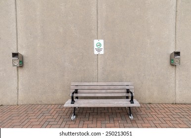 A bench flanked by two ash bins with a designated smoking area sign above.