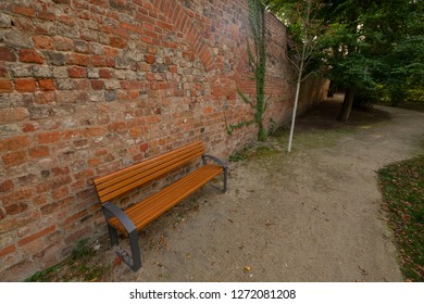 a bench in front of a brick wall
