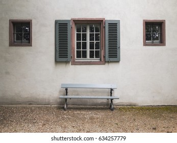 A bench in front of a building with three windows