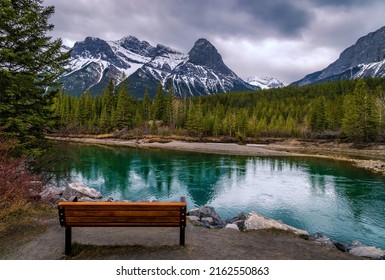 Bench Looking Out Over Canmore Mountains On A Cloudy Day